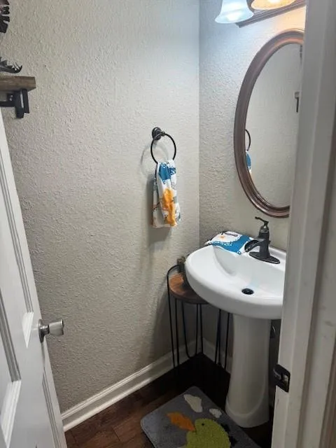 Bathroom with a textured wall and dark wood finished floors