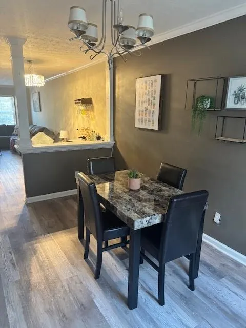 Dining space featuring hanging lights, crown molding, and wood finished floors
