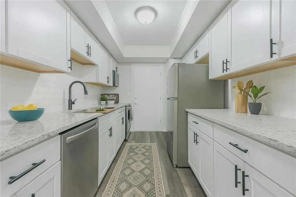 Kitchen with tasteful backsplash, appliances with stainless steel finishes, dark wood-type flooring, a tray ceiling, and white cabinets