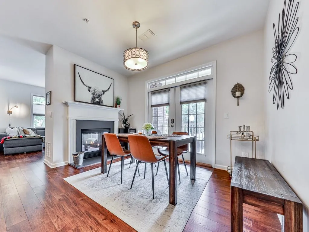 Dining area featuring dark wood finished floors, plenty of natural light, a glass covered fireplace, and french doors