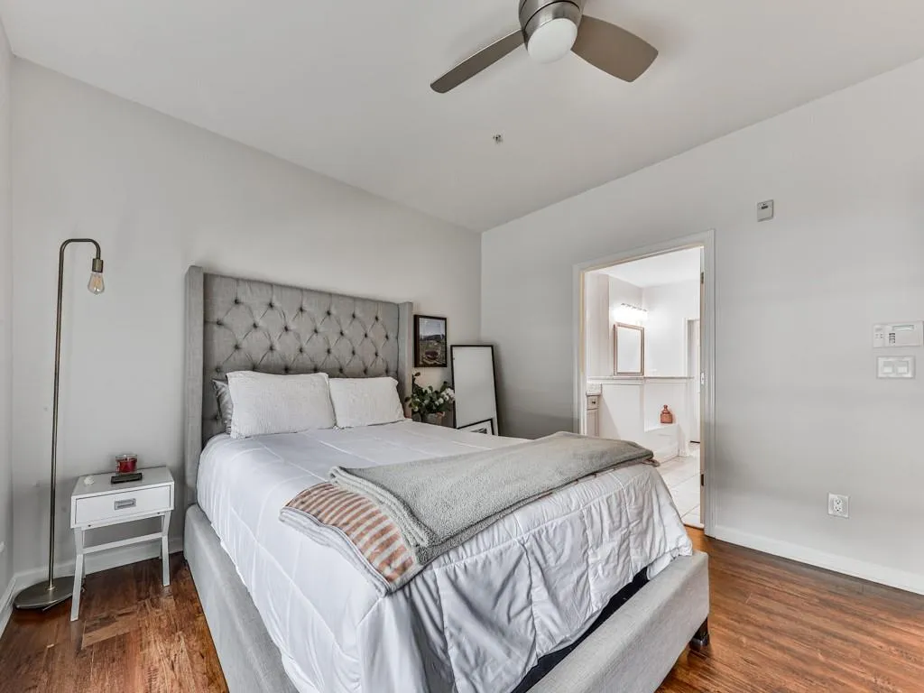 Bedroom featuring wood finished floors, connected bathroom, and a ceiling fan