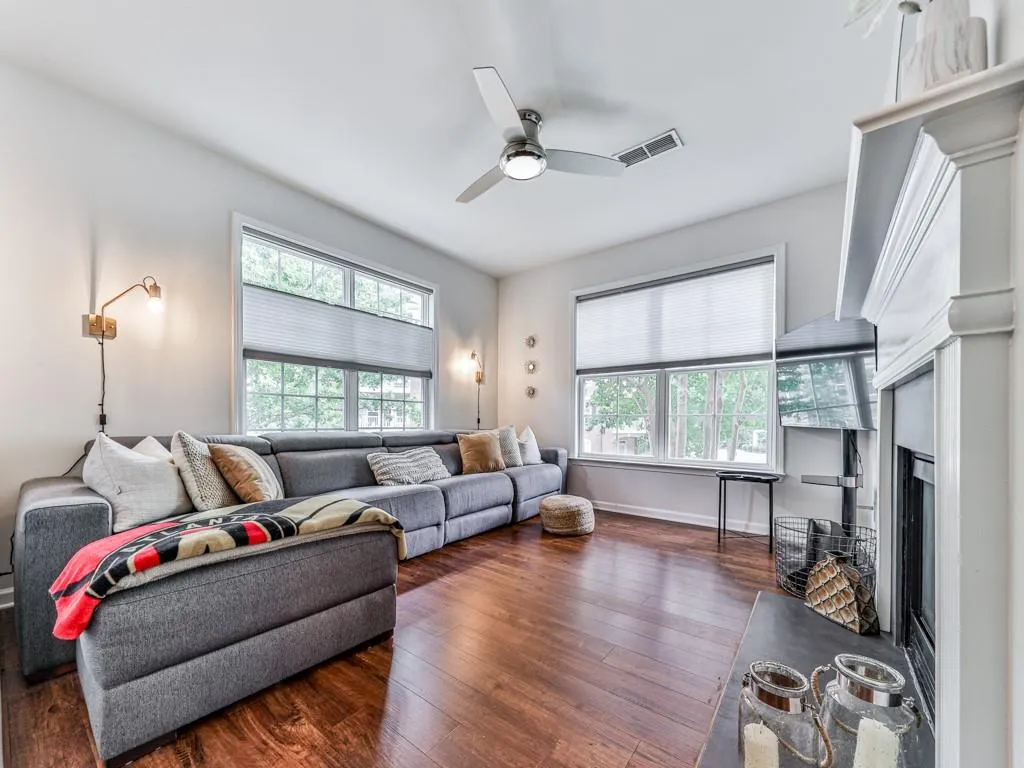 Living area featuring wood-type flooring, a fireplace, and a ceiling fan