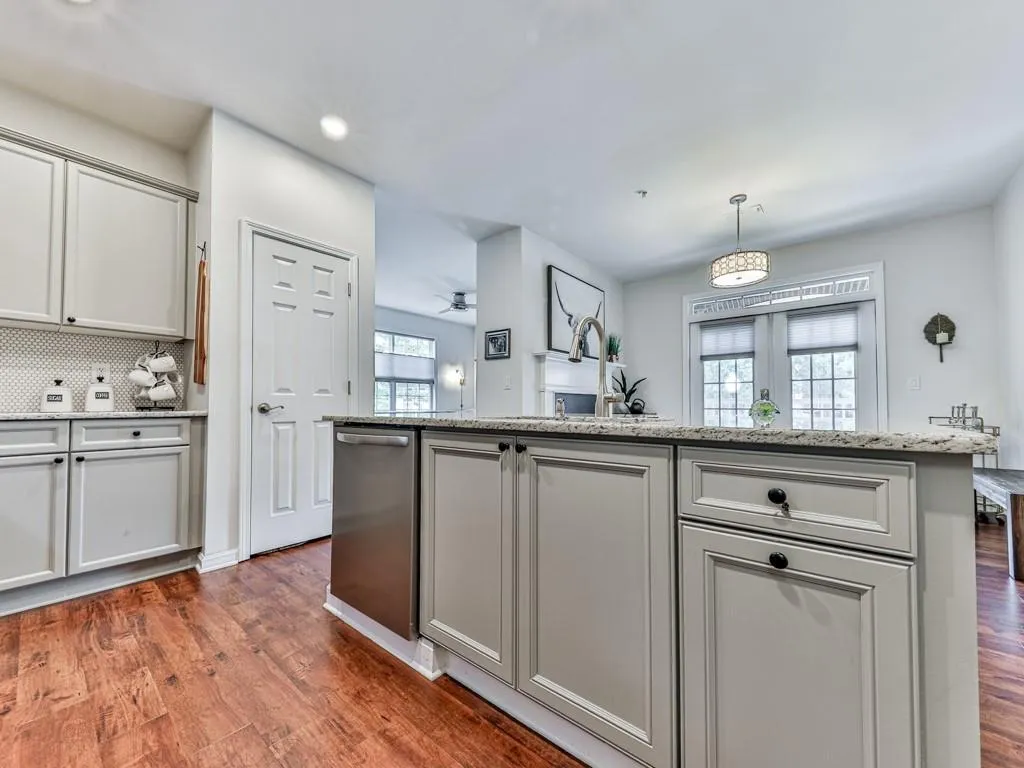 Kitchen featuring dark wood finished floors, backsplash, light stone countertops, dishwasher, and recessed lighting