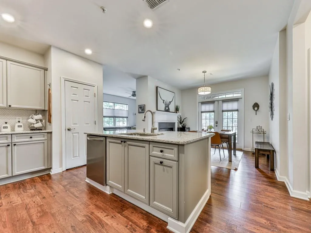 Kitchen featuring dark wood finished floors, decorative backsplash, a center island with sink, recessed lighting, and a fireplace