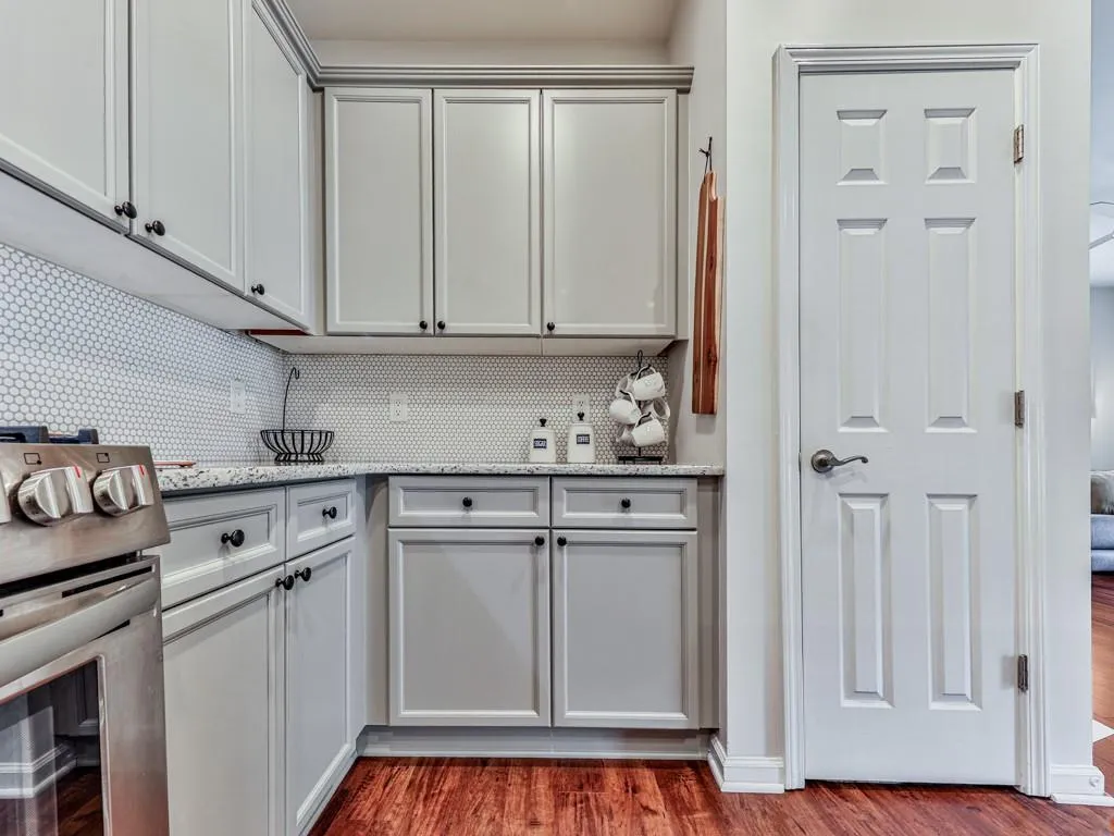 Kitchen with stainless steel range oven, dark wood-type flooring, decorative backsplash, and light stone counters