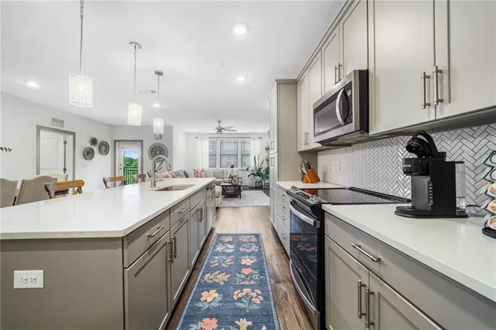 Modern kitchen featuring an extended island with a built-in sink, white countertops, and gray cabinetry