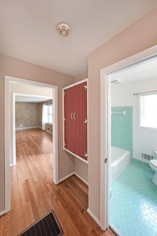 Hallway featuring wood finished floors, plenty of natural light, and baseboards