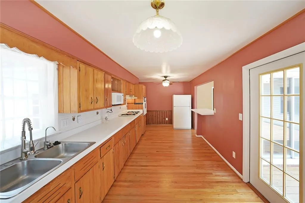 Kitchen with white appliances, a sink, plenty of natural light, and light wood-type flooring
