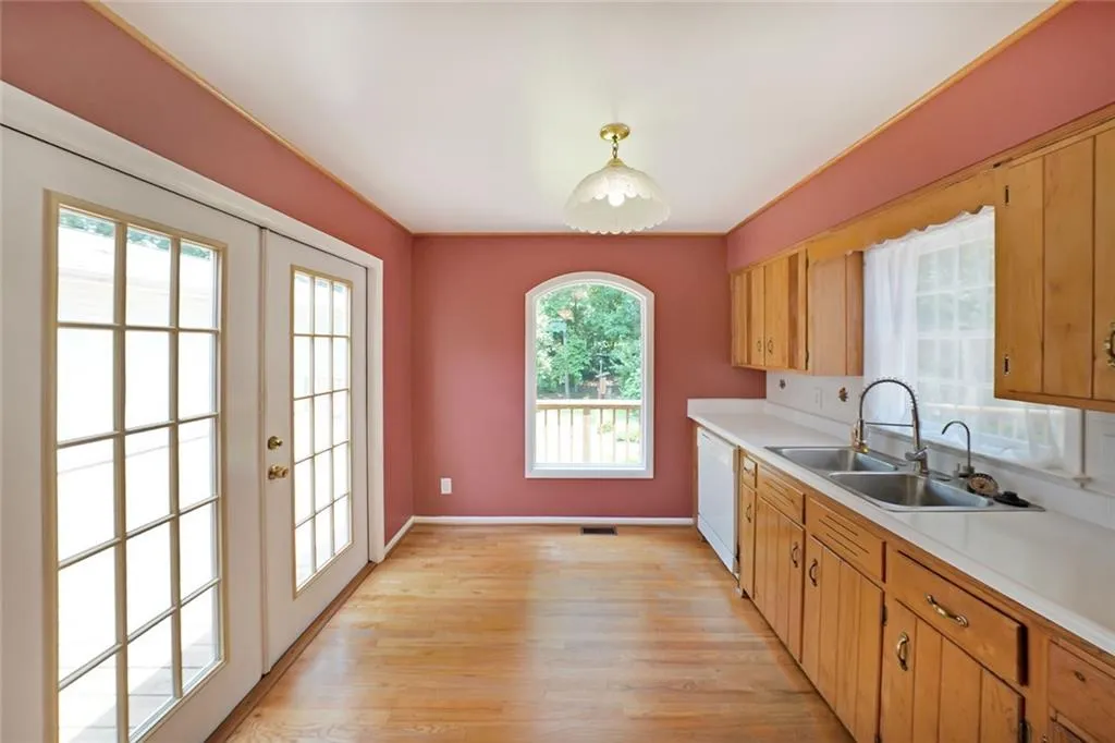 Kitchen with a sink, white dishwasher, light countertops, and light wood-type flooring
