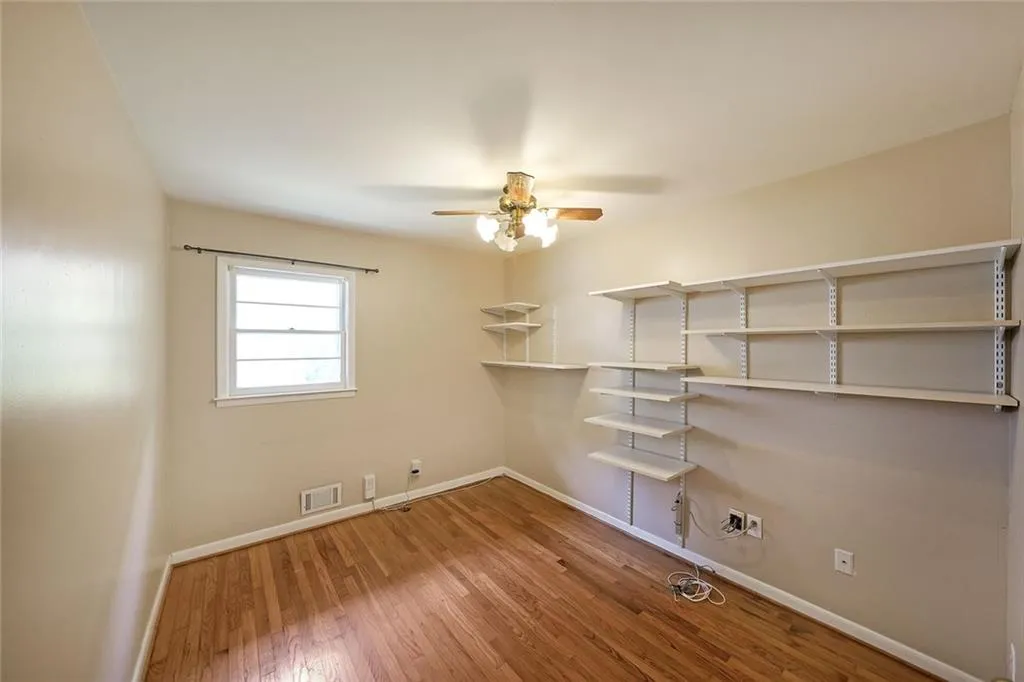 Unfurnished room with a ceiling fan, baseboards, and wood finished floors