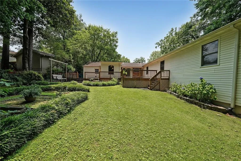View of grassy yard with a deck and stairs