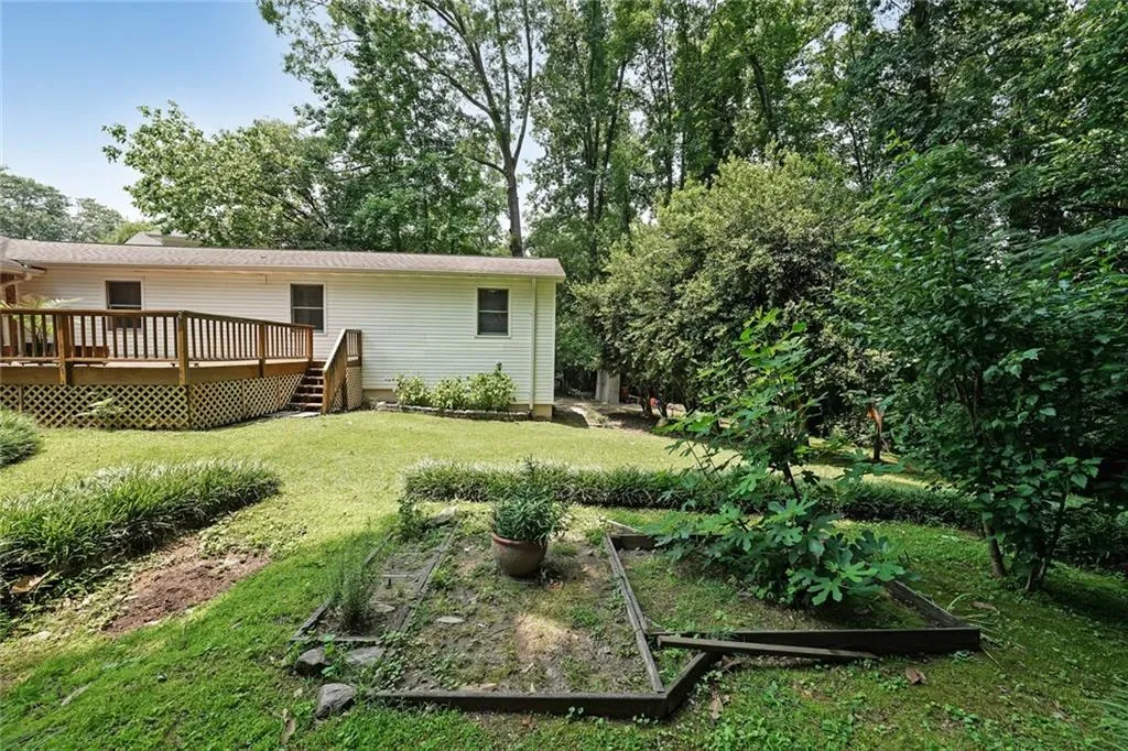 View of green lawn featuring a garden and a deck