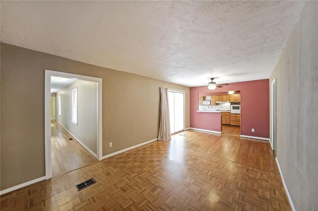 Unfurnished living room with a textured ceiling, baseboards, a ceiling fan, and parquet flooring