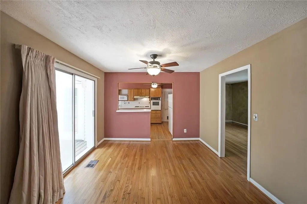 Unfurnished living room with a ceiling fan, light wood-style flooring, baseboards, and a textured ceiling