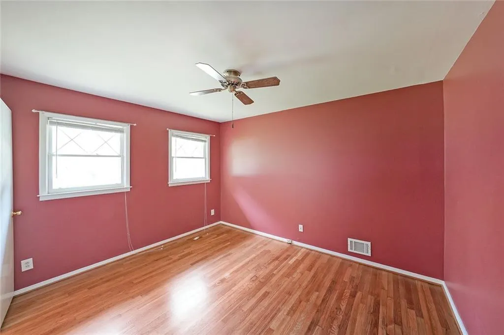 Empty room with light wood finished floors, a ceiling fan, and baseboards