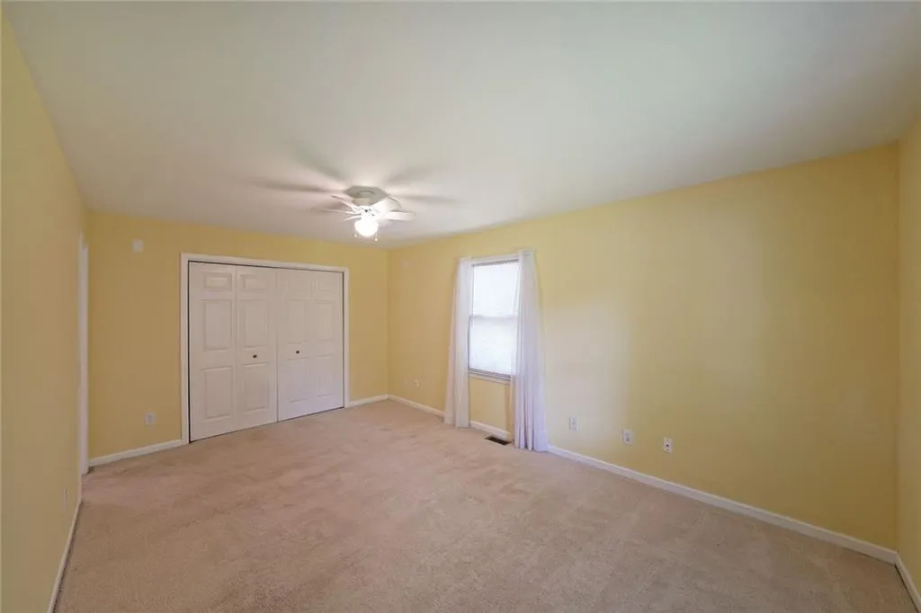 Unfurnished bedroom with light carpet, baseboards, a closet, and a ceiling fan