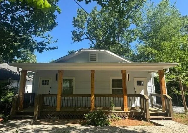 Front facade featuring light blue siding, a covered porch with natural wood posts, and white window frames