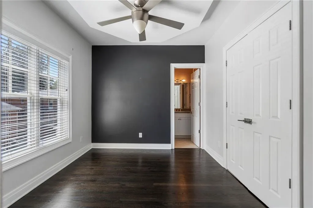 Unfurnished bedroom featuring dark wood-style flooring, connected bathroom, and a ceiling fan Unfurnished bedroom featuring dark wood-style flooring, connected bathroom, and a ceiling fan