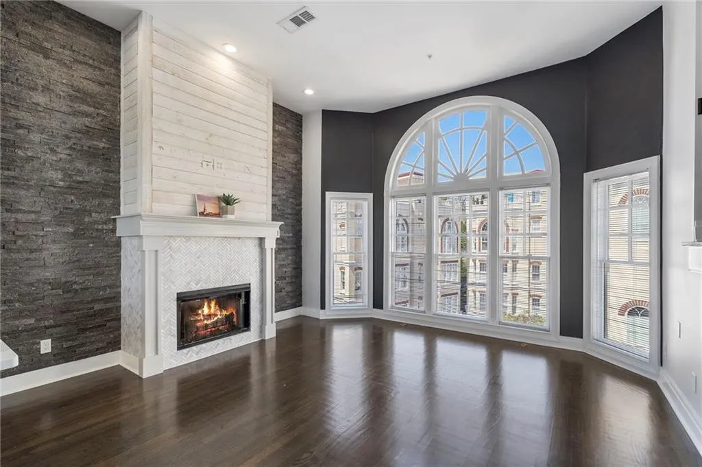 Unfurnished living room featuring dark wood-style floors, a fireplace, a high ceiling, and recessed lighting Unfurnished living room featuring dark wood-style floors, a fireplace, a high ceiling, and recessed lighting