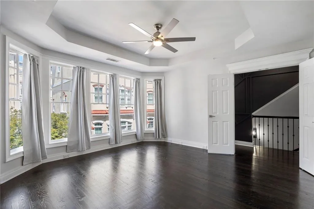 Spare room with a tray ceiling, dark wood-type flooring, and a ceiling fan Spare room with a tray ceiling, dark wood-type flooring, and a ceiling fan