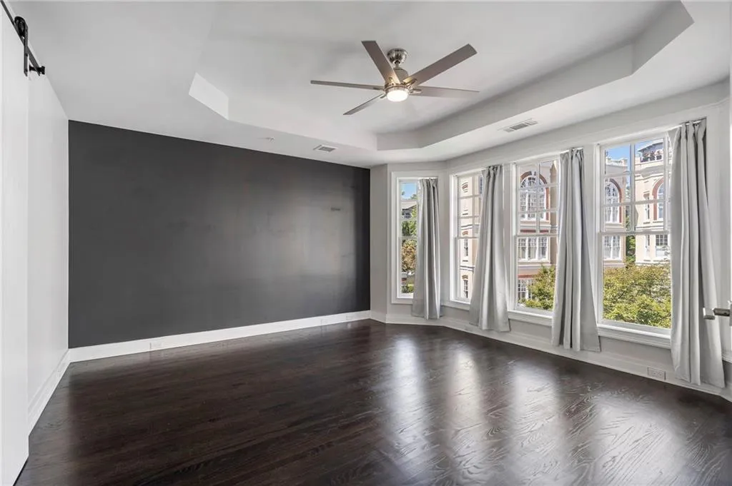 Spare room with a raised ceiling, dark wood-style flooring, and a ceiling fan Spare room with a raised ceiling, dark wood-style flooring, and a ceiling fan