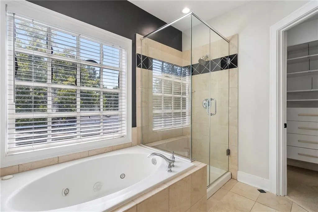 Bathroom featuring light tile patterned floors, a whirlpool tub, and a stall shower Bathroom featuring light tile patterned floors, a whirlpool tub, and a stall shower