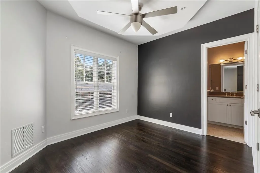 Unfurnished bedroom featuring dark wood-style flooring, a ceiling fan, and ensuite bath Unfurnished bedroom featuring dark wood-style flooring, a ceiling fan, and ensuite bath