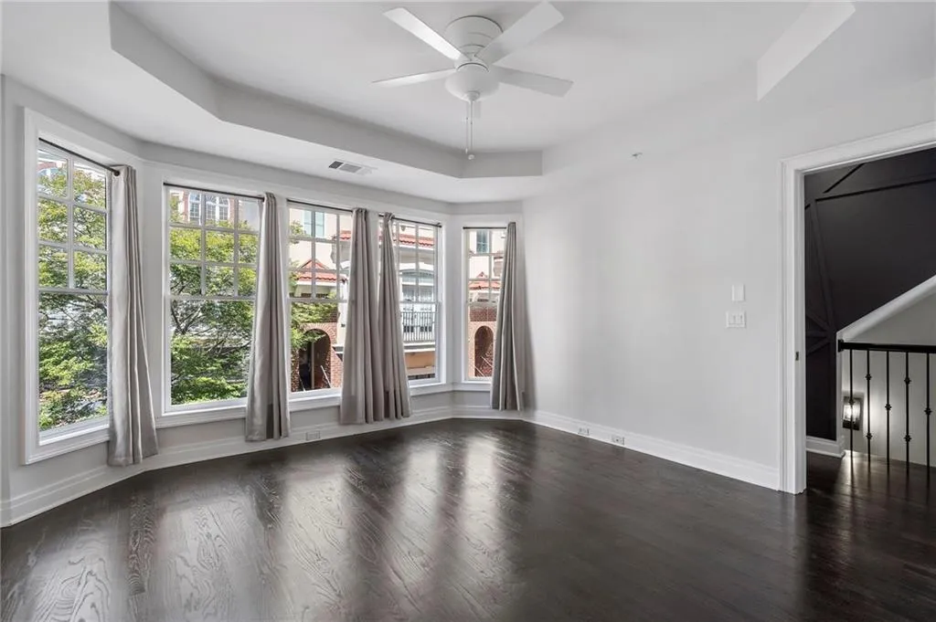 Unfurnished room featuring a tray ceiling, dark wood-style flooring, and ceiling fan Unfurnished room featuring a tray ceiling, dark wood-style flooring, and ceiling fan