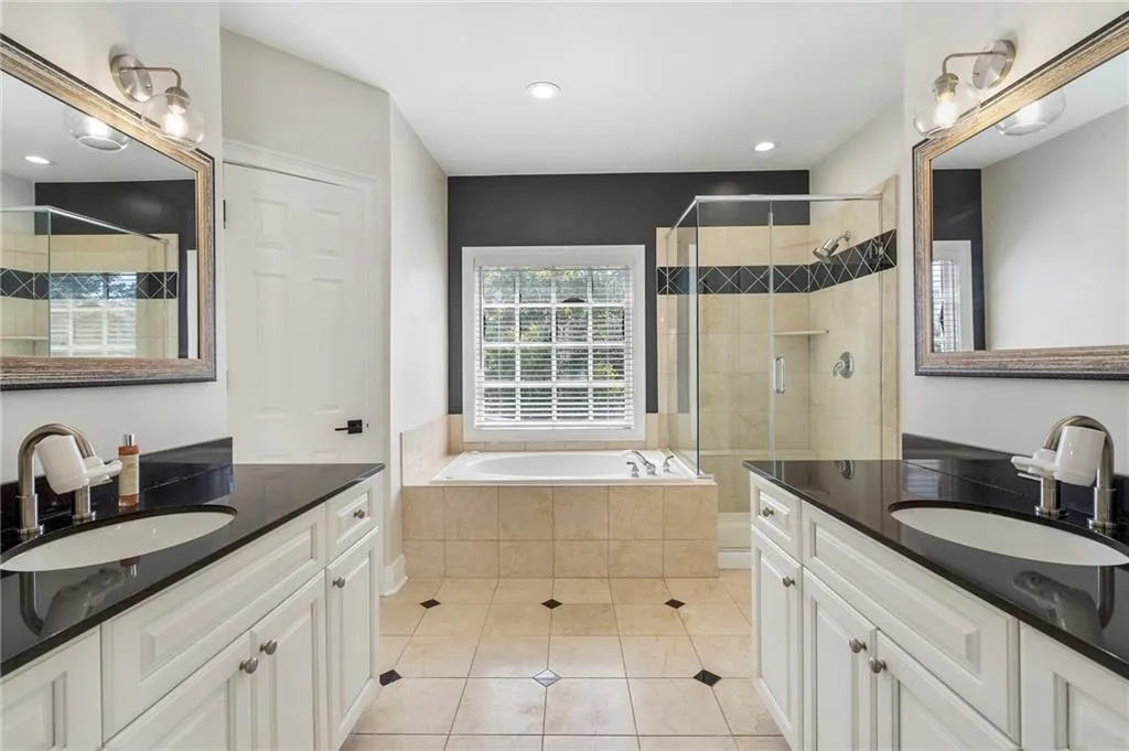 Bathroom featuring two vanities, light tile patterned floors, a garden tub, a tile shower, and recessed lighting Bathroom featuring two vanities, light tile patterned floors, a garden tub, a tile shower, and recessed lighting