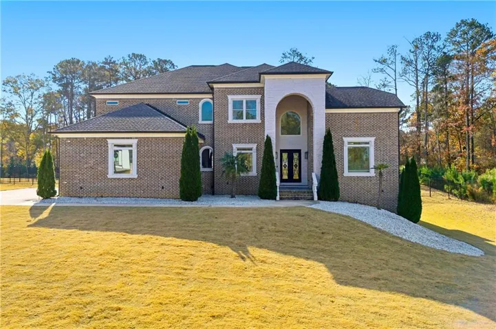 Brick exterior with a prominent arched entry, dark double entry doors, and arched windows