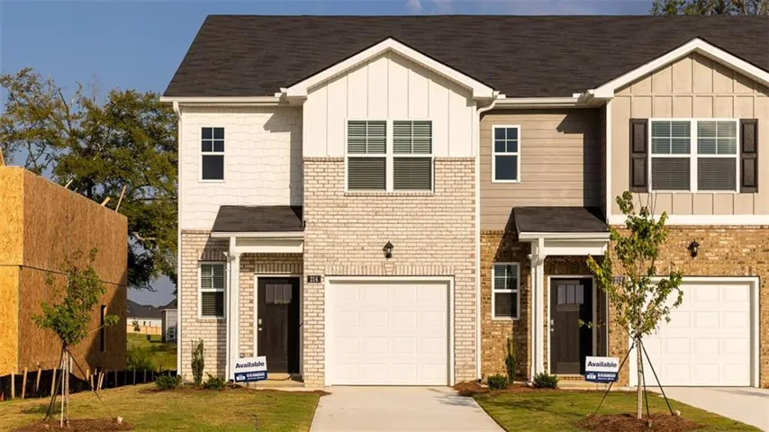 Exterior featuring brick veneer, vertical and horizontal siding, attached garage, and dark-paneled entry door