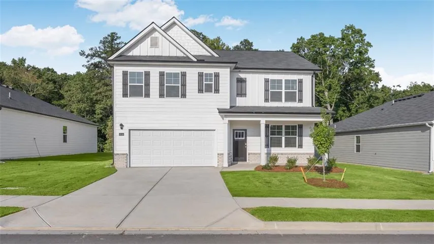 Two-story residence featuring white siding, dark shutters, an attached two-car garage, and a covered entry
