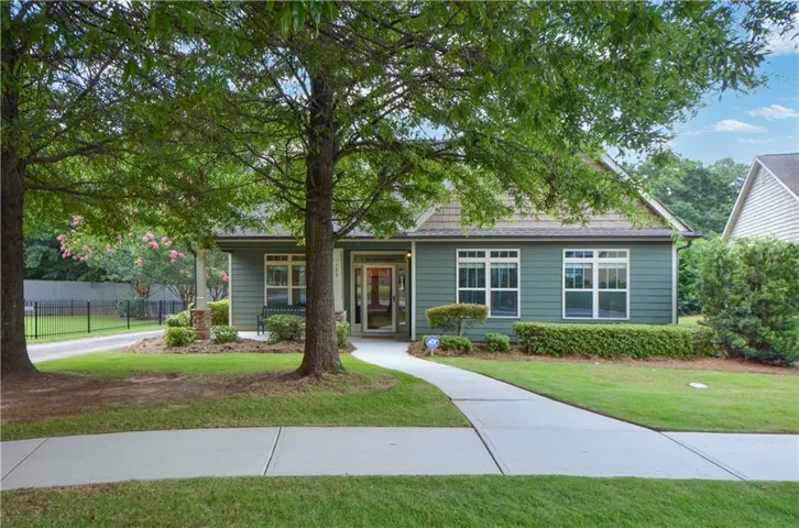 Ranch-style exterior with green siding, a covered front porch, and a concrete walkway