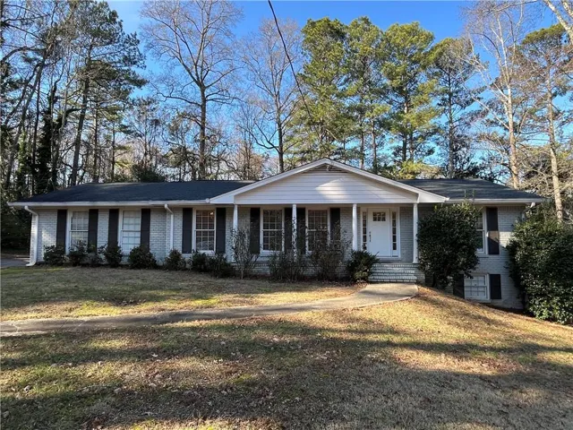 Traditional ranch-style residence featuring a brick facade with painted gray brick, dark shutters, and a prominent front entry with a white door
