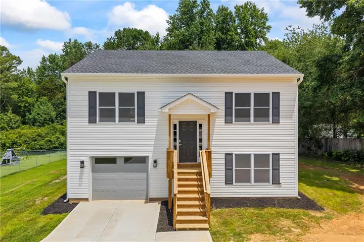 Two-story residence featuring white vinyl siding and a dark shingle roof