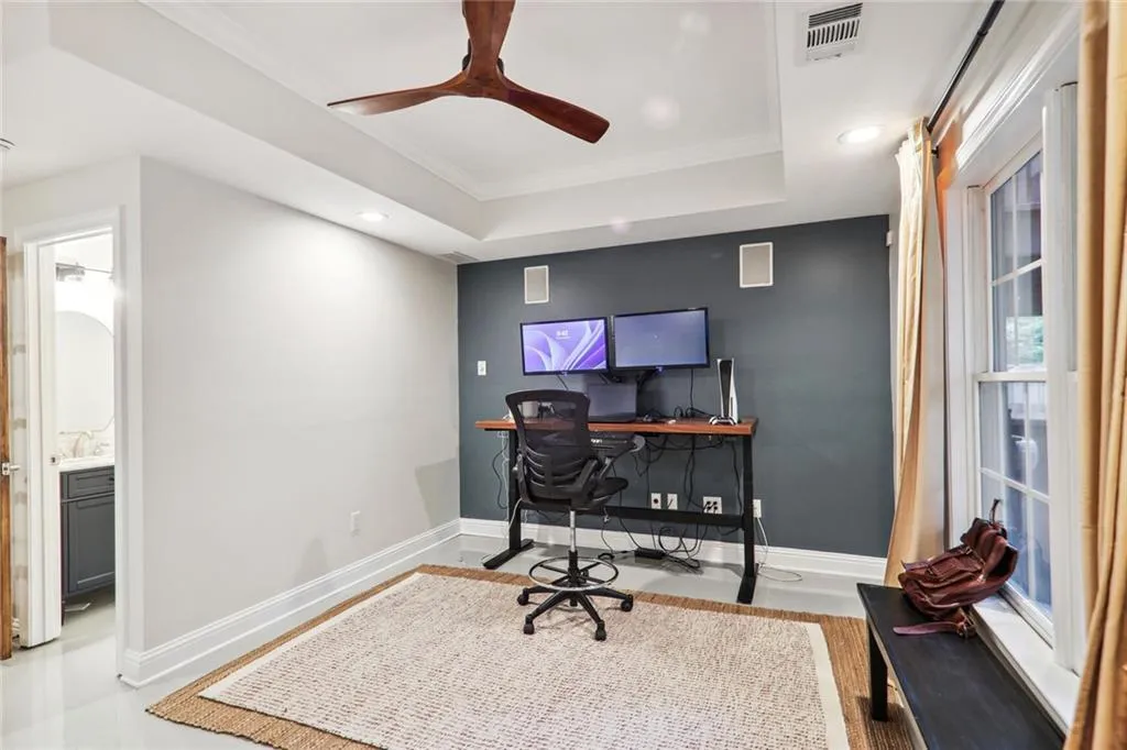 Home office with ceiling fan, light hardwood / wood-style flooring, a raised ceiling, sink, and ornamental molding