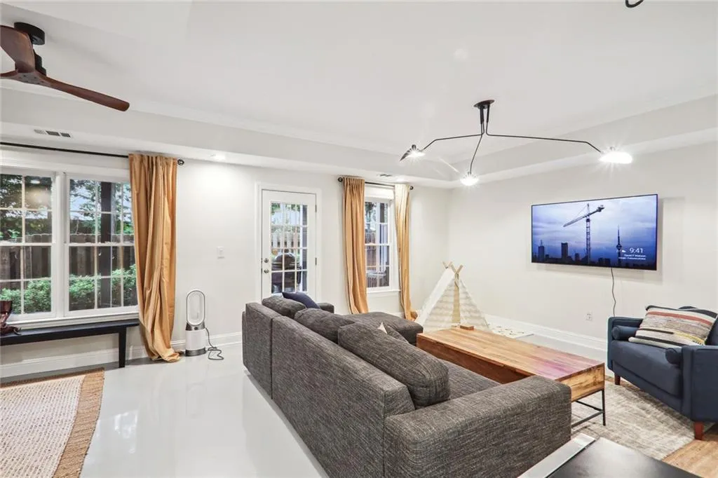 Living room featuring wood-type flooring, ornamental molding, and ceiling fan