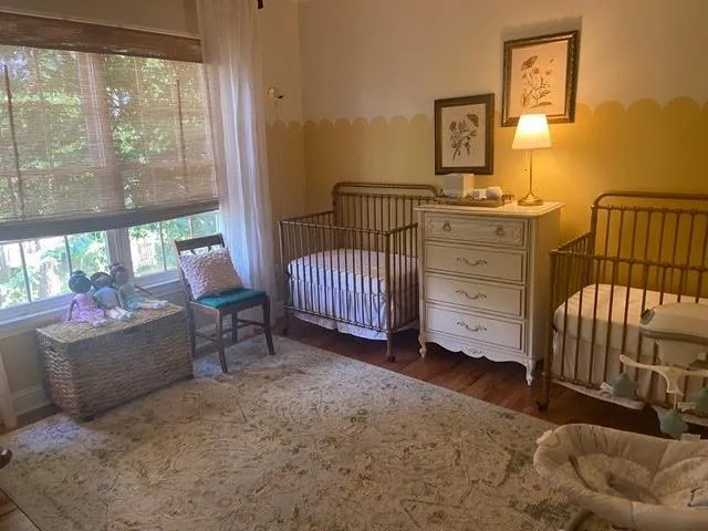 Bedroom with a nursery area and dark hardwood / wood-style floors