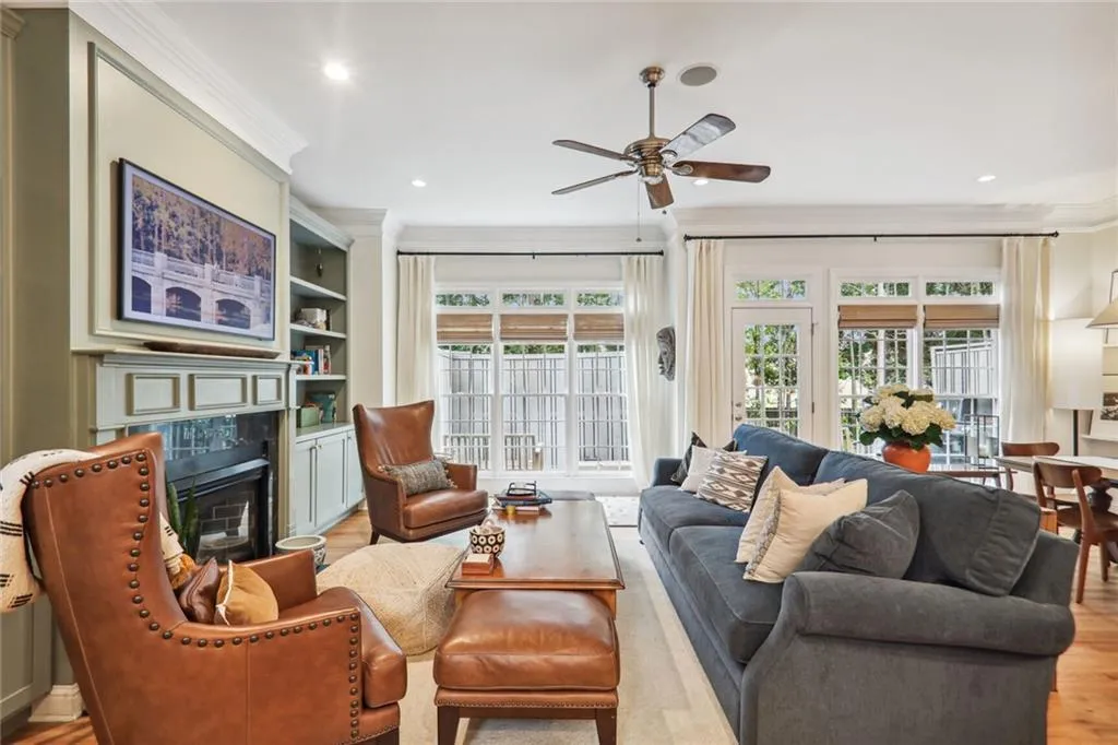 Living room featuring ornamental molding, light wood-type flooring, a healthy amount of sunlight, and a tiled fireplace