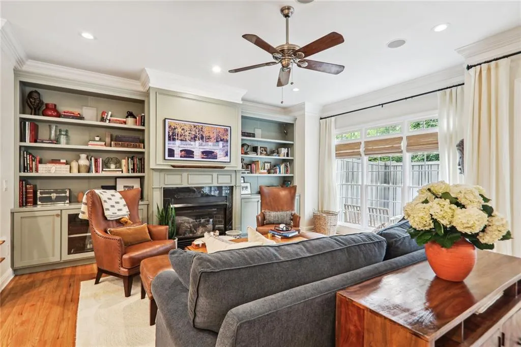 Living room with ceiling fan, light hardwood / wood-style floors, a premium fireplace, ornamental molding, and built in shelves