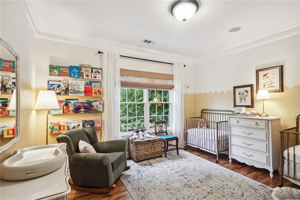 Bedroom with crown molding, a crib, and dark wood-type flooring