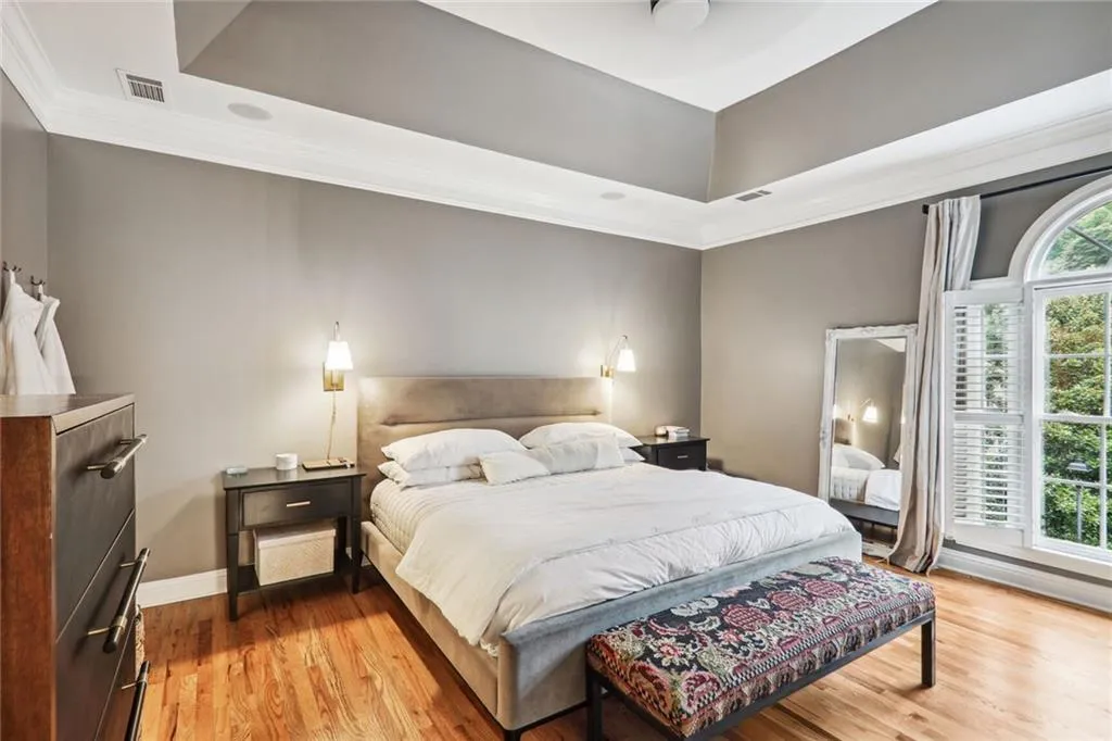 Bedroom with light wood-type flooring, crown molding, and a tray ceiling