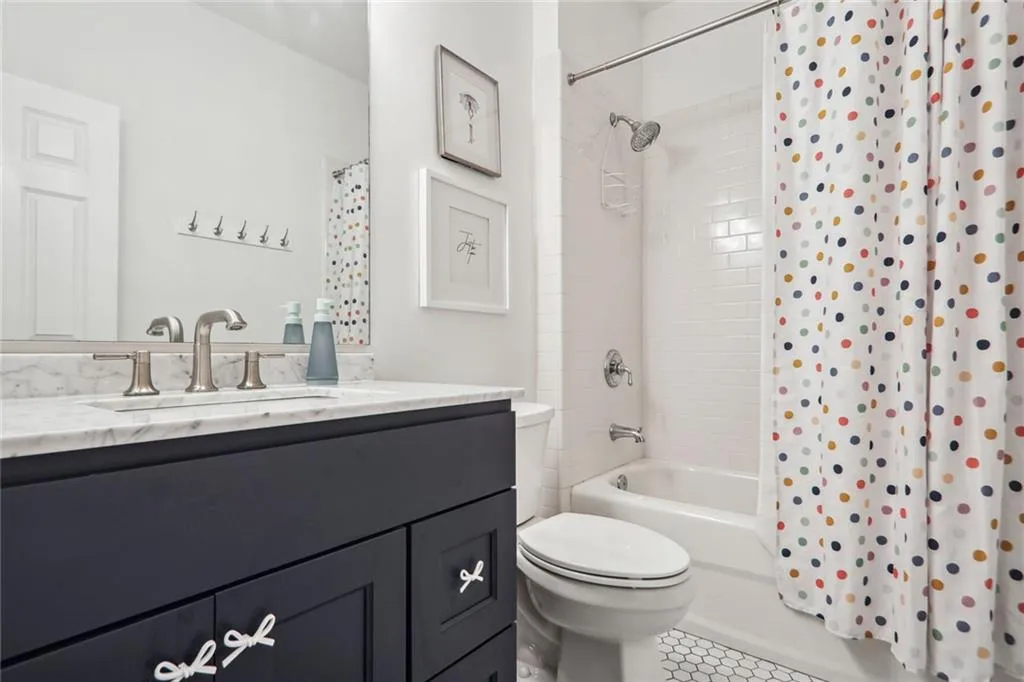 Full bathroom featuring vanity, shower / bath combo with shower curtain, toilet, and tile patterned flooring