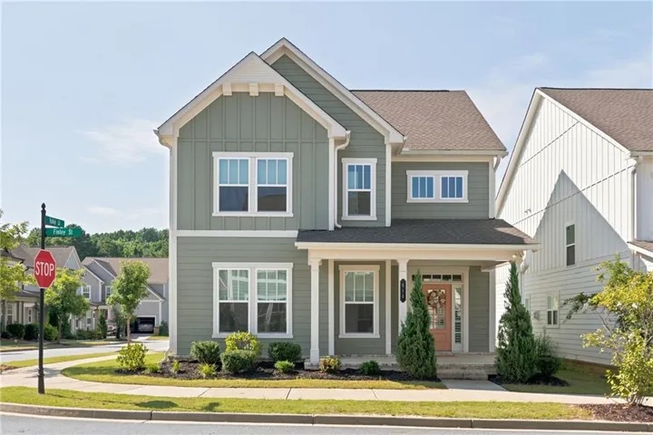 Two-story residence featuring a gabled roofline and light green siding with white trim