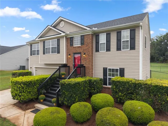 Two-story residence featuring brick and siding exterior, a red entry door, and a two-car garage