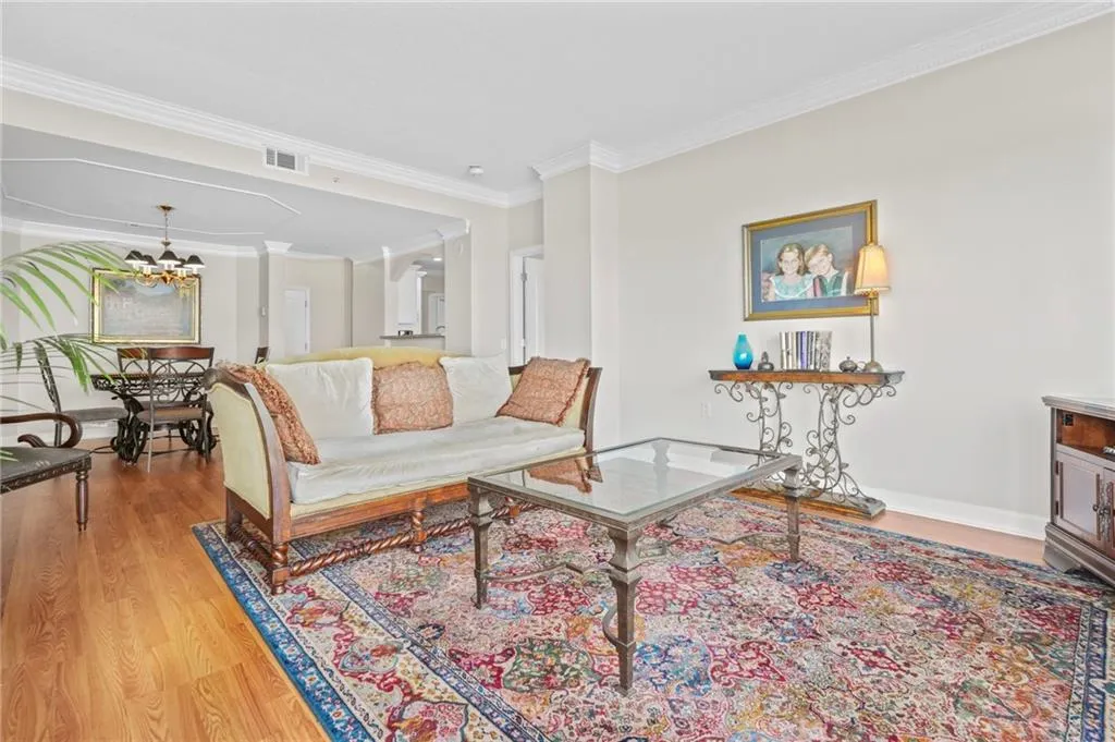 Living area featuring wood finished floors, ornamental molding, baseboards, and a chandelier