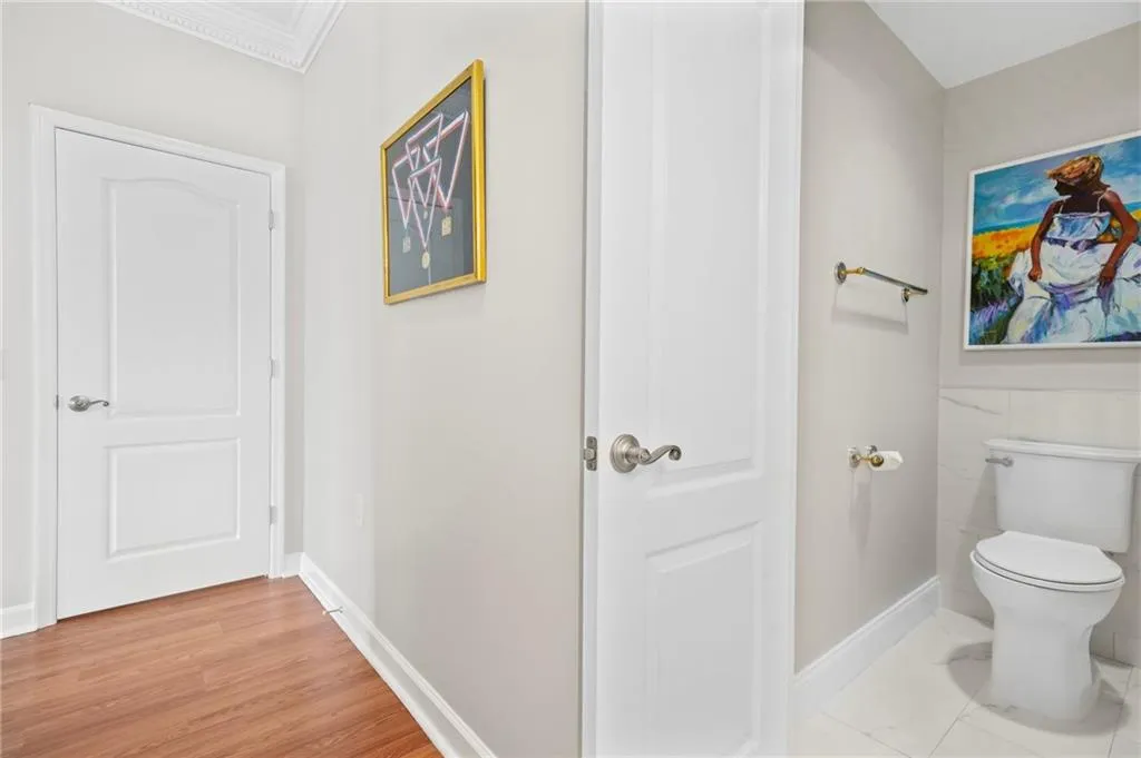 Bathroom featuring toilet, ornamental molding, and baseboards