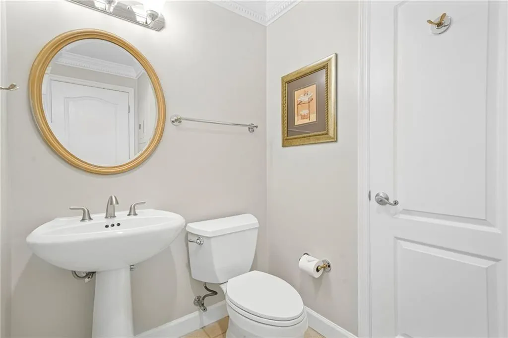 Bathroom with toilet, baseboards, and crown molding