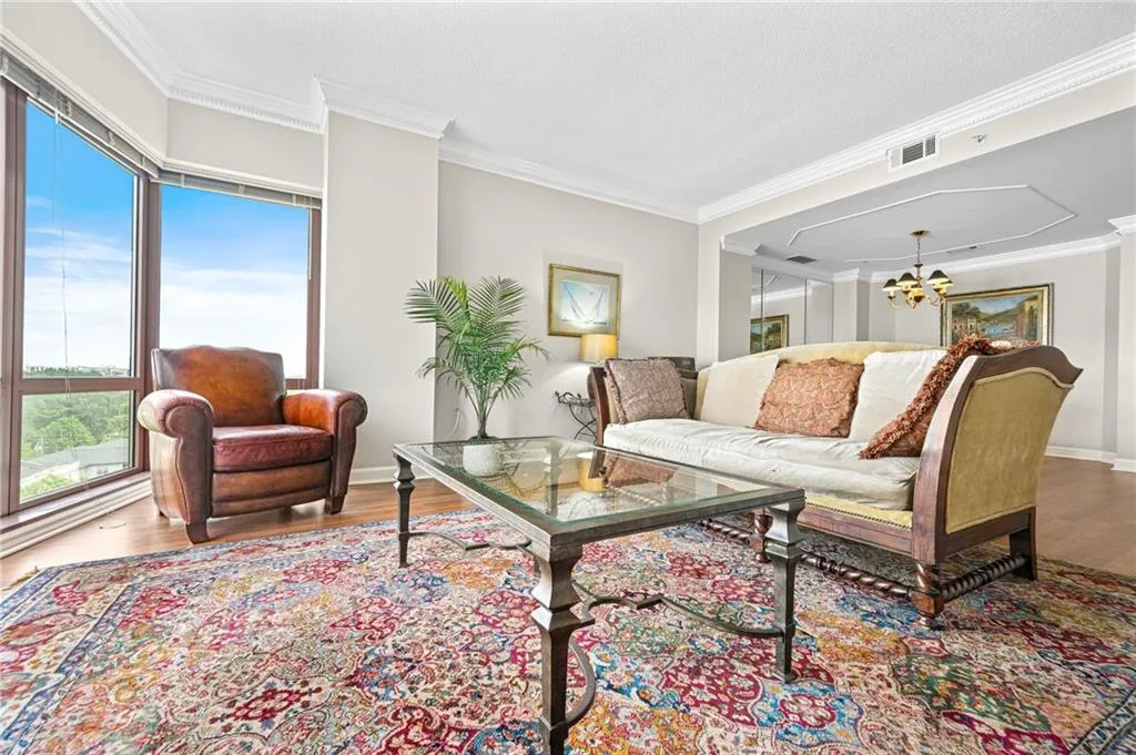 Living room featuring wood finished floors, a chandelier, crown molding, and baseboards