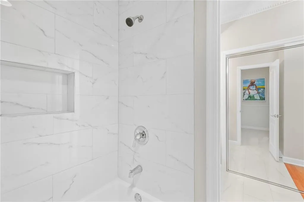 Bathroom featuring baseboards, shower / tub combination, and marble finish flooring